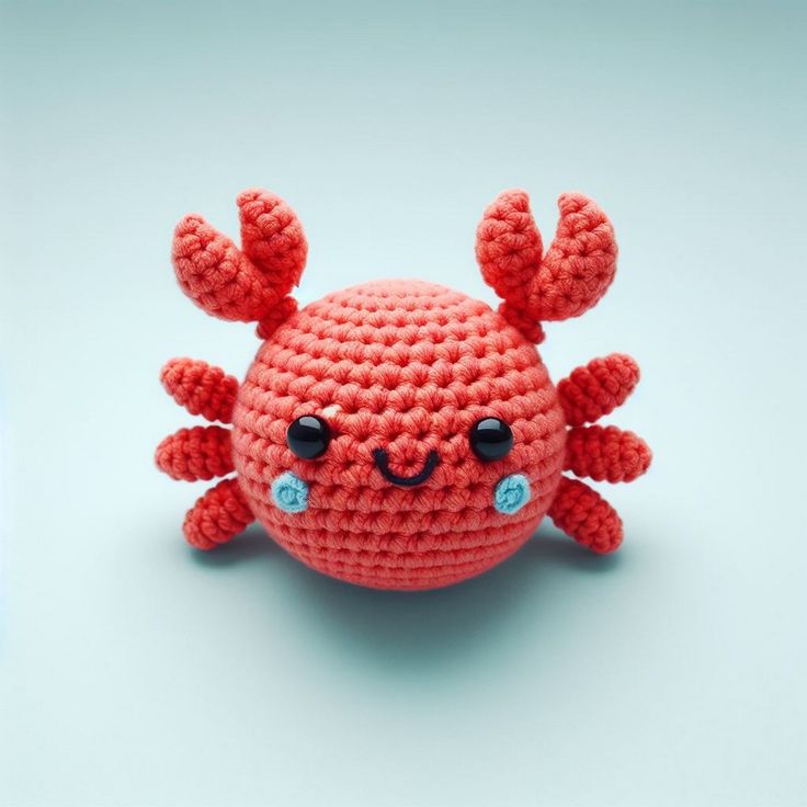 an orange crocheted crab sitting on top of a white table next to a blue wall