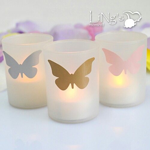 three lit candles with butterflies on them