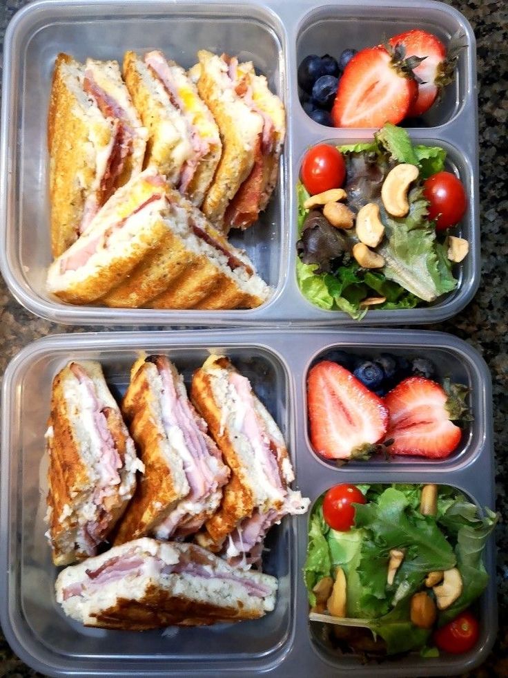 three plastic containers filled with different types of sandwiches and fruit on top of a table