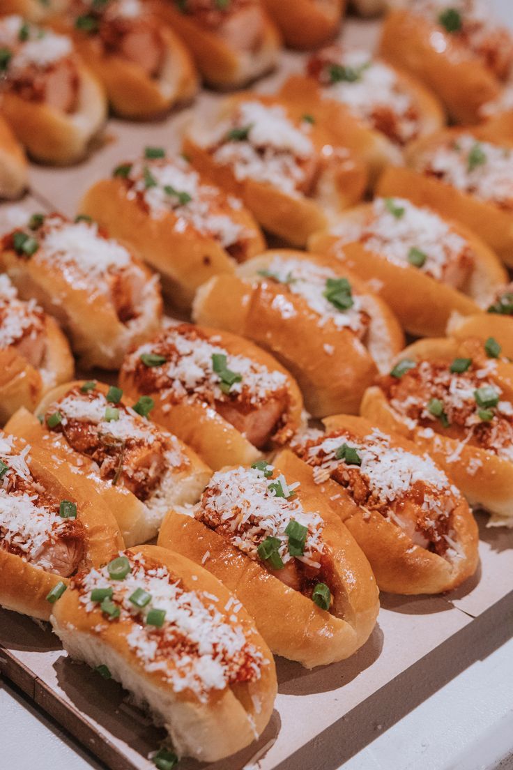 many hot dogs are covered in powdered sugar and garnished with green onions