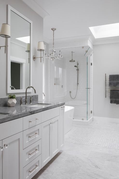 a white bathroom with marble counter tops and double sinks