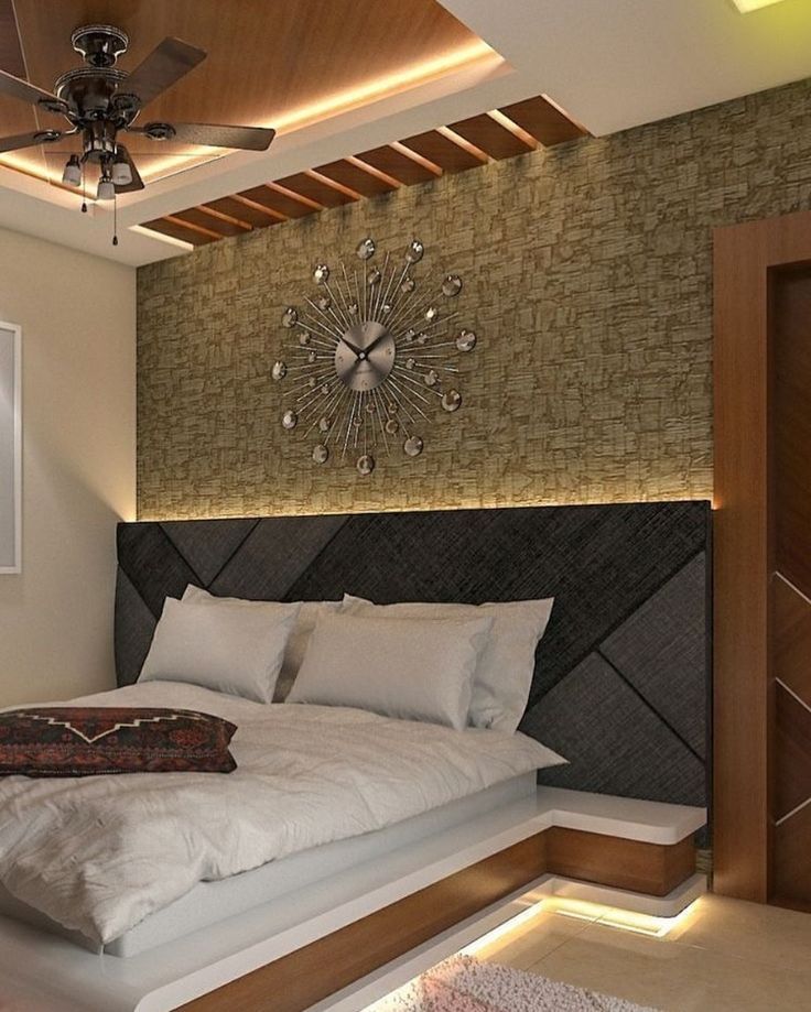 a large bed sitting under a ceiling fan next to a wall mounted clock in a bedroom