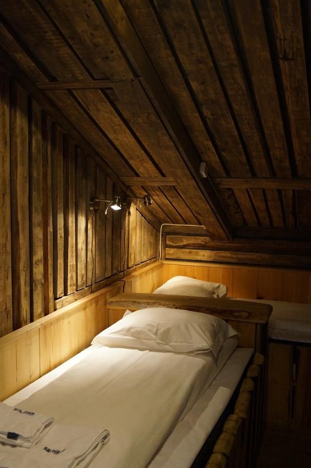 two beds in a small room with wooden walls