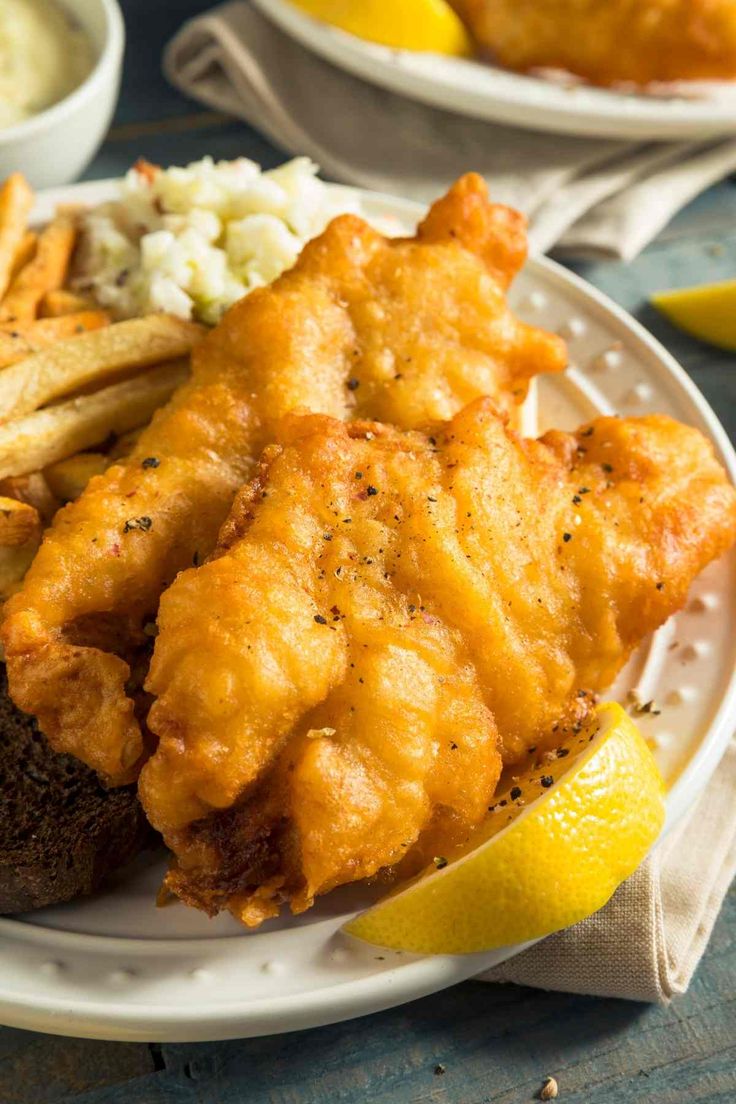 fish and chips on a plate with lemon wedges