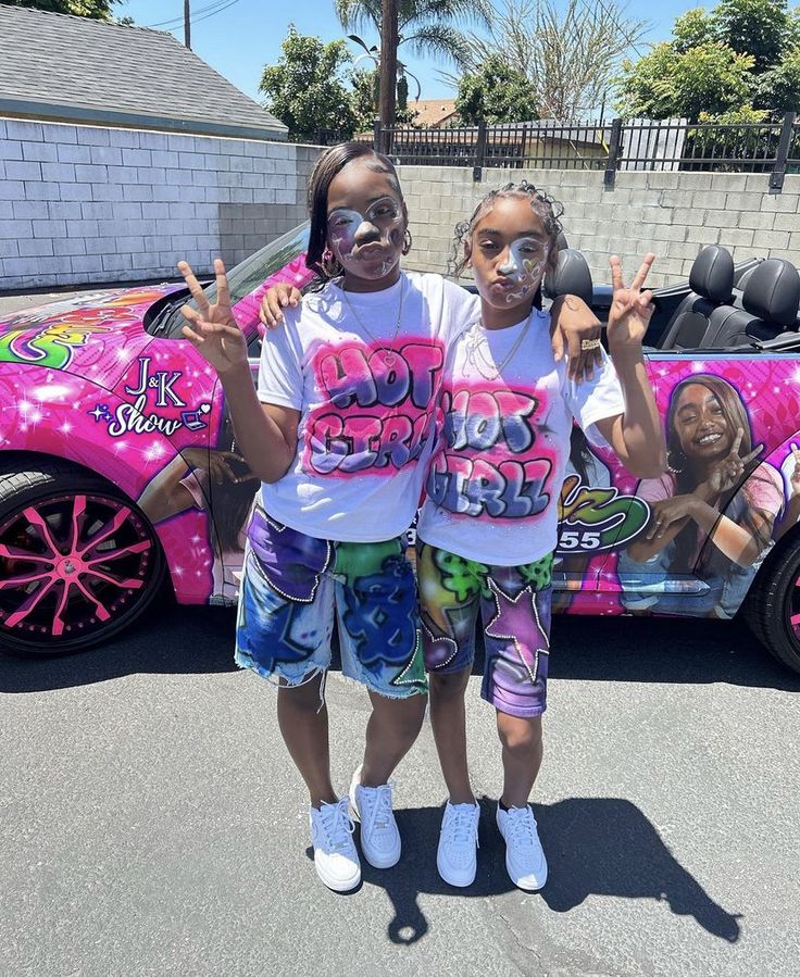 two girls standing in front of a pink car