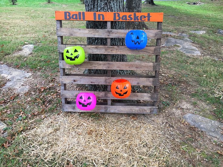 a wooden pallet with pumpkin faces painted on it and an orange sign that says ball in basket