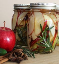 three jars filled with apple slices and herbs