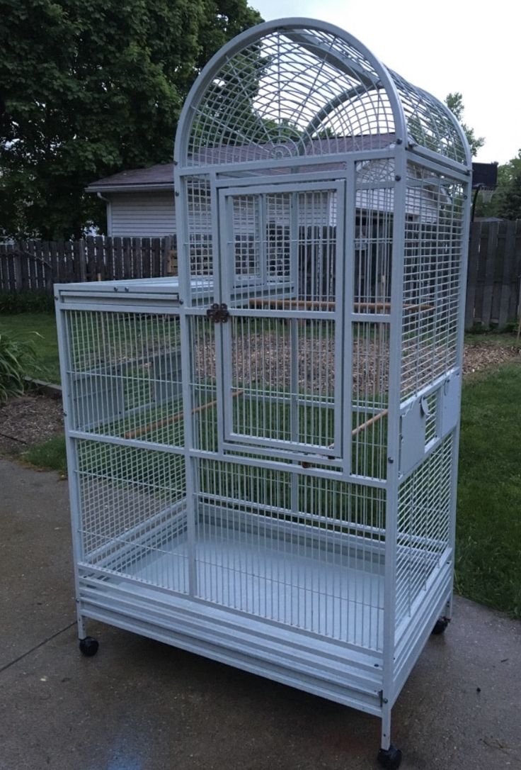 a white bird cage sitting on top of a sidewalk