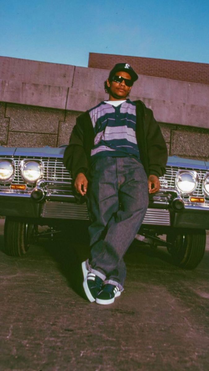 a man laying on the ground next to a parked car with his feet propped up