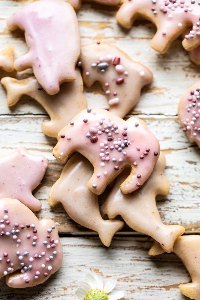 decorated cookies with pink frosting and sprinkles on a wooden table next to a flower