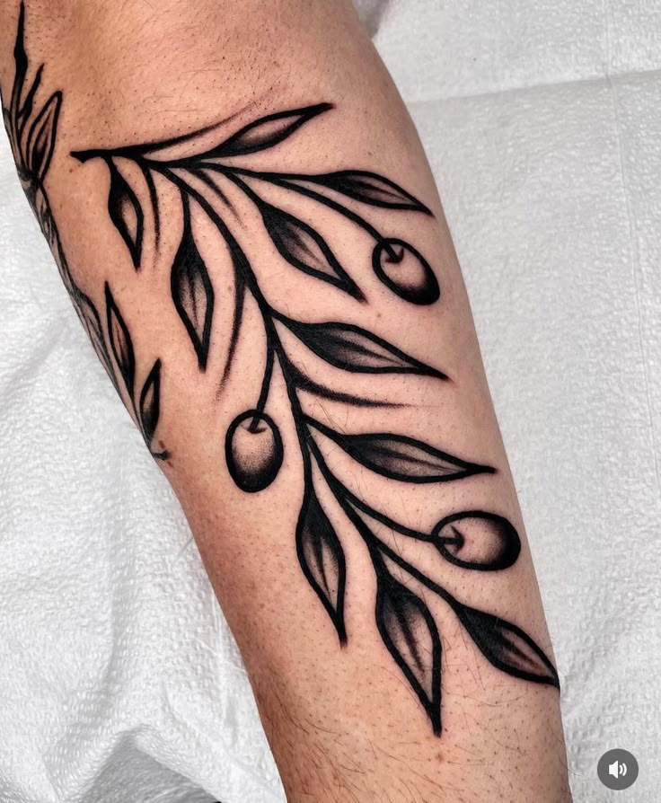 a close up of a person's arm with an olive branch tattoo on it