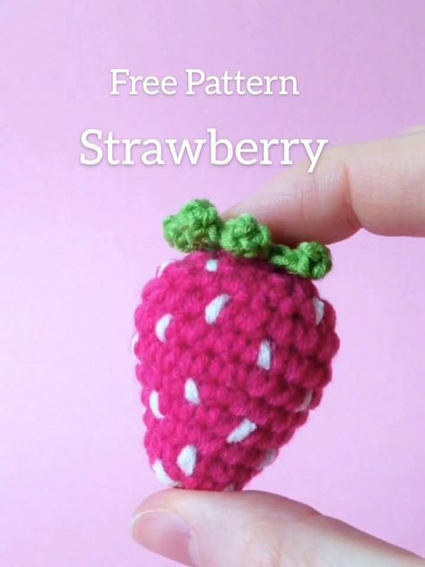 a small crocheted strawberry being held up by someone's hand with the words kostenlose anleiting erdbee