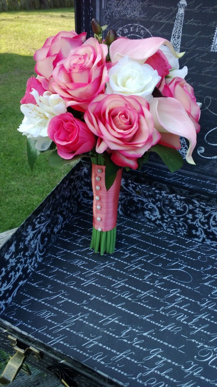 pink and white flowers in a vase on top of an open trunk with writing underneath