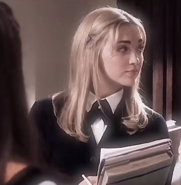 a woman in a black shirt and tie holding a binder looking at another woman