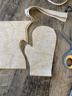 two pieces of felt with scissors and thread on the table next to it, one piece has been cut out