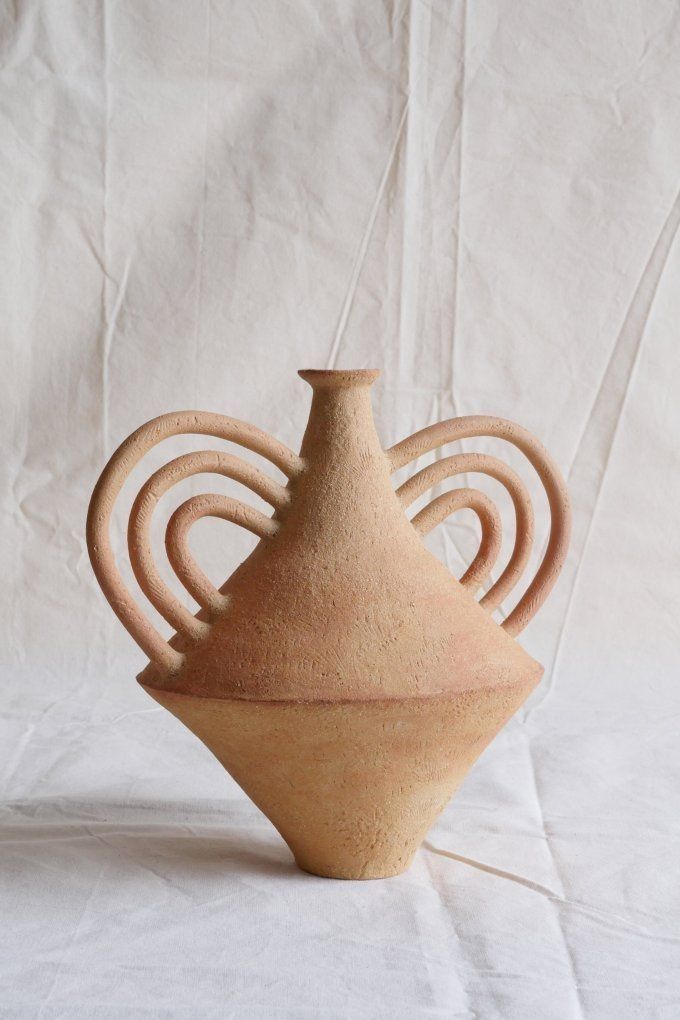 a clay vase sitting on top of a white sheet