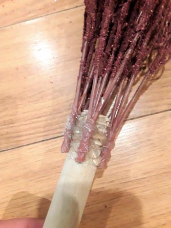 someone is holding up some purple flowers on a wooden table and it looks like they have long stems attached to them