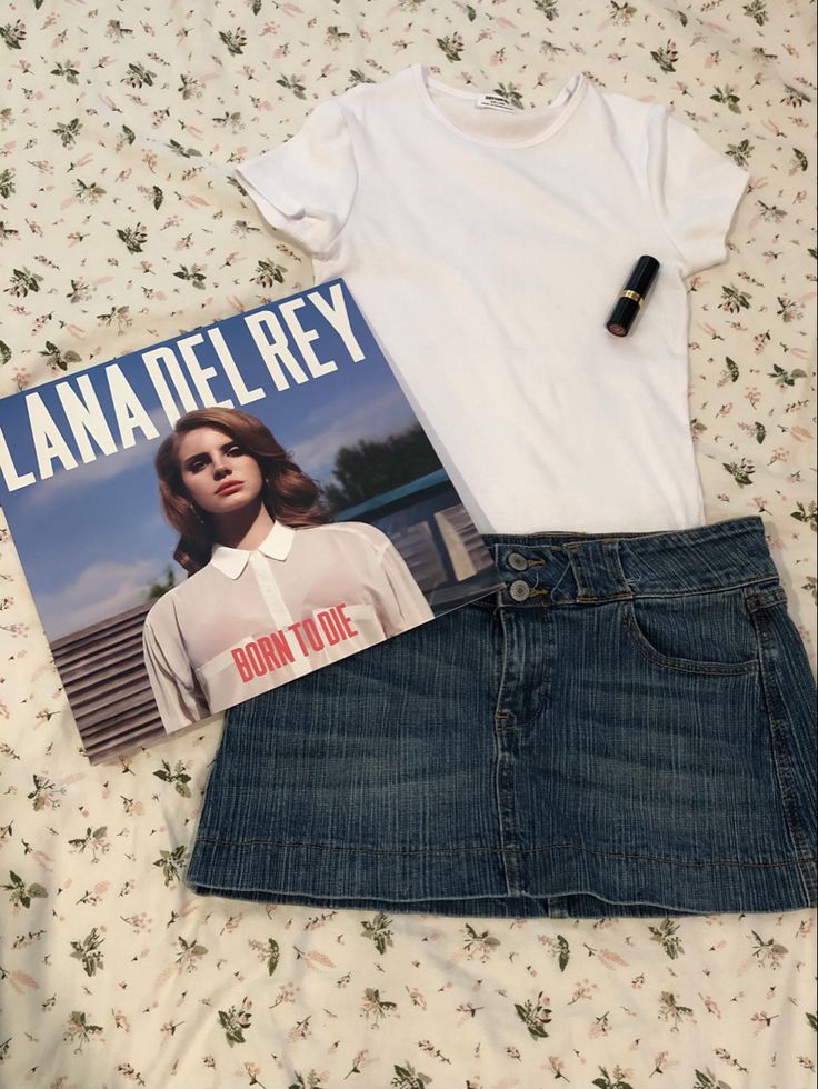 a white shirt and jean skirt are on the bed next to a t - shirt