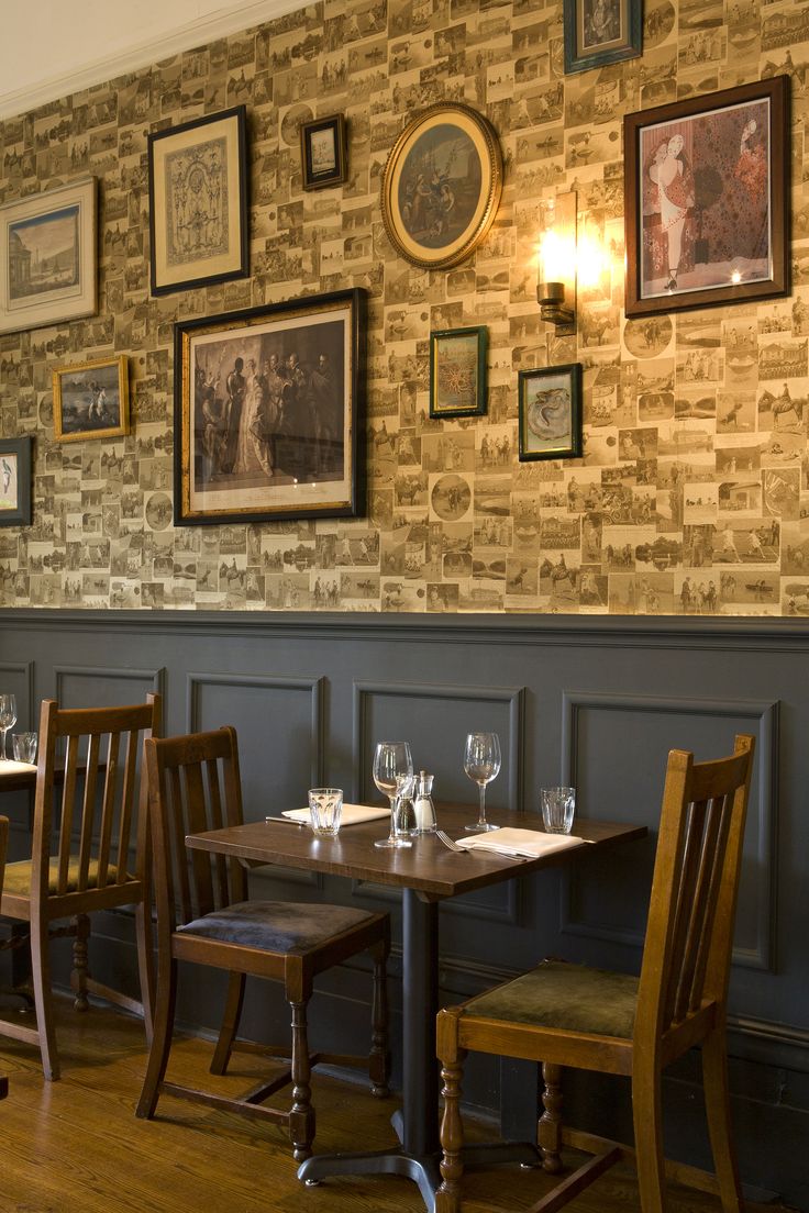 a restaurant with wooden tables and chairs in front of a brick wall that has pictures on it