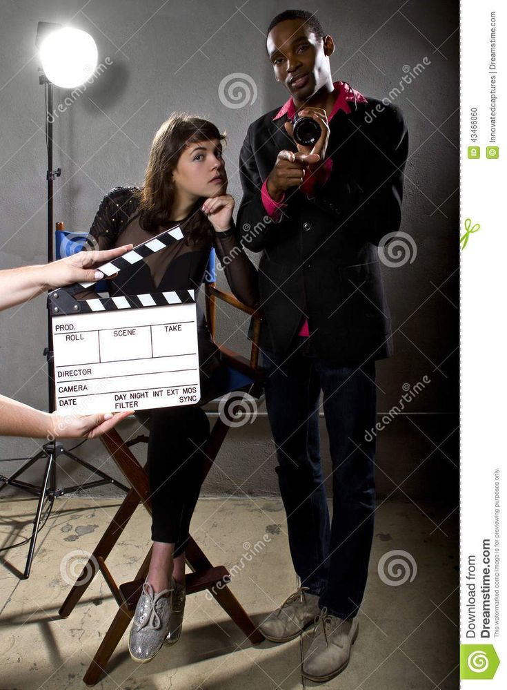 a man and woman standing next to each other in front of a movie clapper