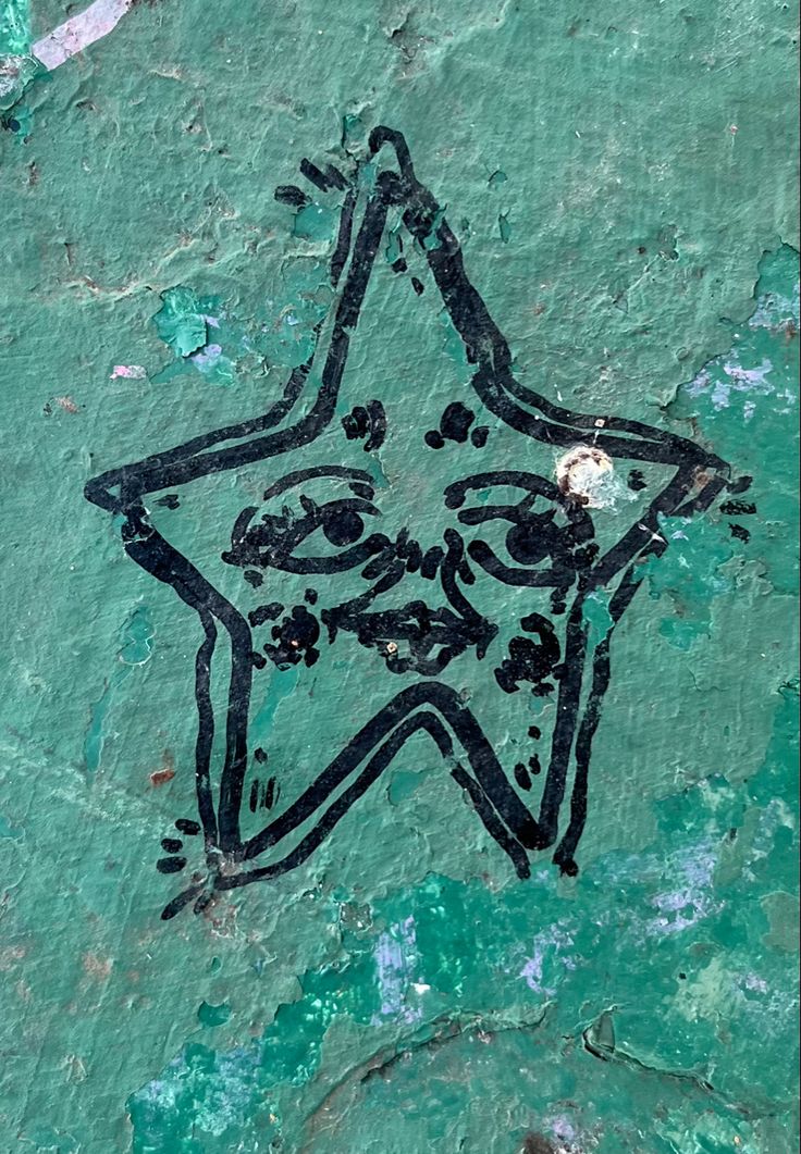 a star is drawn on the side of a green wall with blue paint and black ink