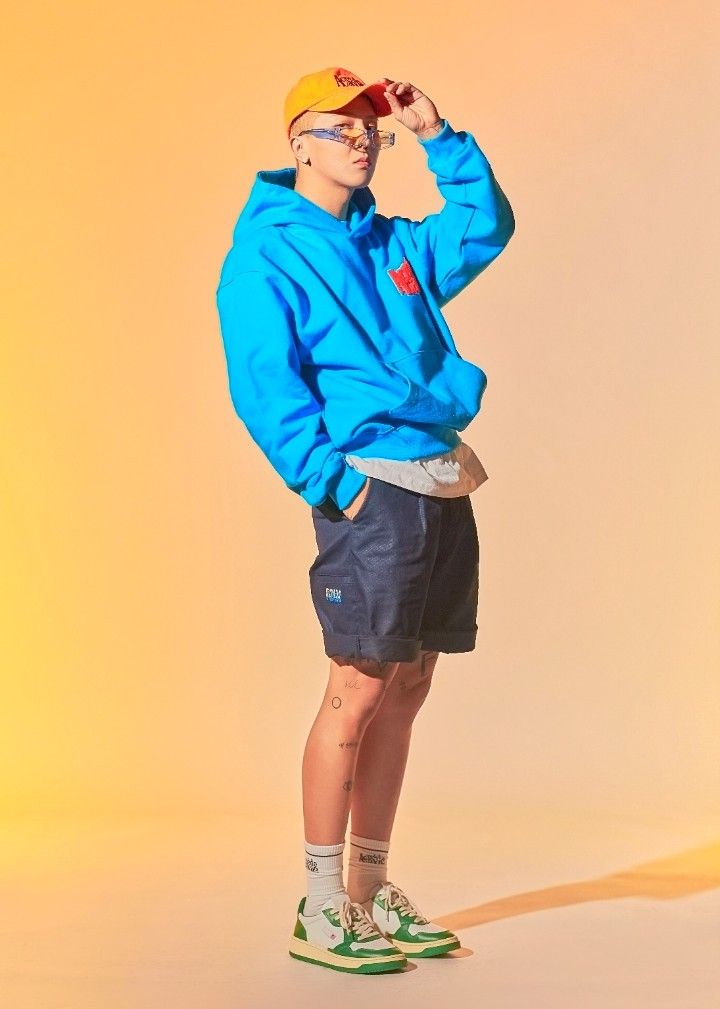 a man in blue hoodie and shorts standing with his hands on his head while looking off to the side