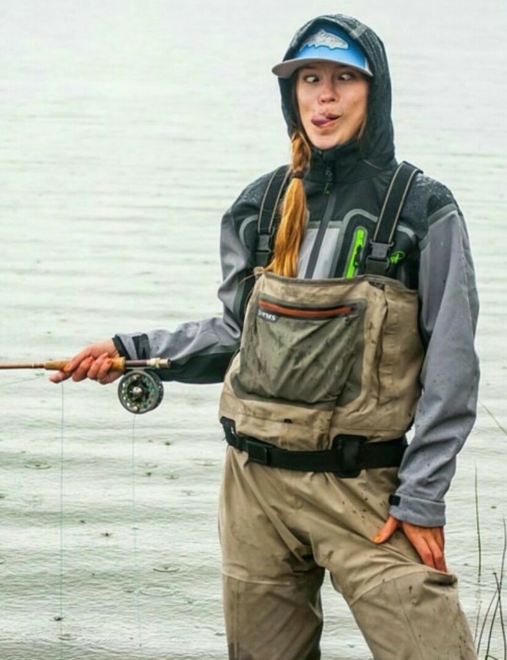 a woman standing in the water holding a fishing rod