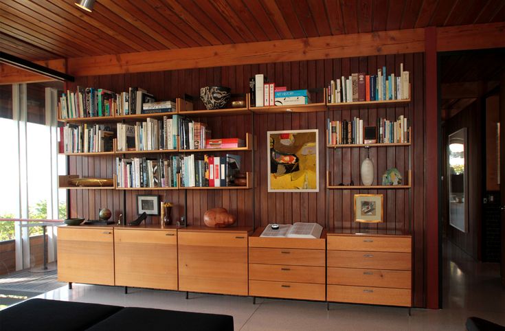 a living room filled with lots of furniture and bookshelves on top of wooden shelves