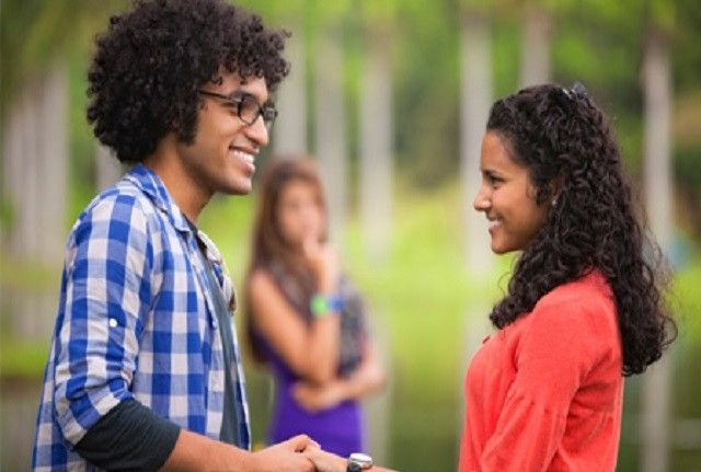 two people standing next to each other with trees in the background and one person shaking hands