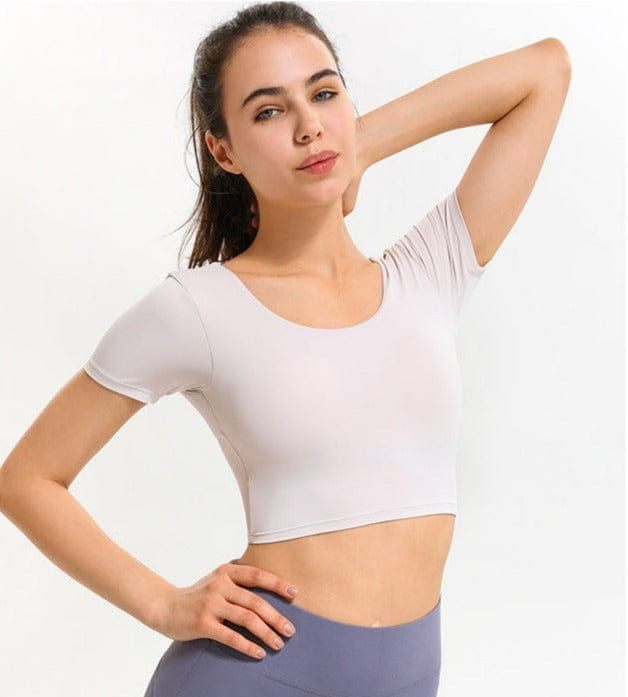 The EMES SHOP shirt details a low scoop backwithshortsleeves and a body hugging fit. Designed with crossing straps in the back. this classic. simple. and comfortable top will transform the way you perceive active wear.MATERIAL:78% Nylon 22% SpandexMEASUREMENTS:X-Small : 0-2 Waist: 23.5-25 in Chest: 31.5-33 inSmall : 4-6 Waist: 25-26.5 in Chest: 33-34.5 inMedium : 6-8 Waist: 26.5-28 in Chest: 34.5-36 inLarge : 8-10 Waist: 28-29.5 in Chest: 36-37.5 in High Stretch Short Sleeve Tops With Built-in Bra, Seamless Short Sleeve T-shirt For Gym, Solid Top With Built-in Bra And Scoop Back, Stretch Short Sleeve Crop Top With Built-in Bra, High Stretch Yoga Top With Scoop Back, Compressive Scoop Back Top For Yoga, Versatile Seamless Short Sleeve Tops, Solid Color Short Sleeve Tops With Built-in Bra, Sports Tops With Built-in Bra And Scoop Back