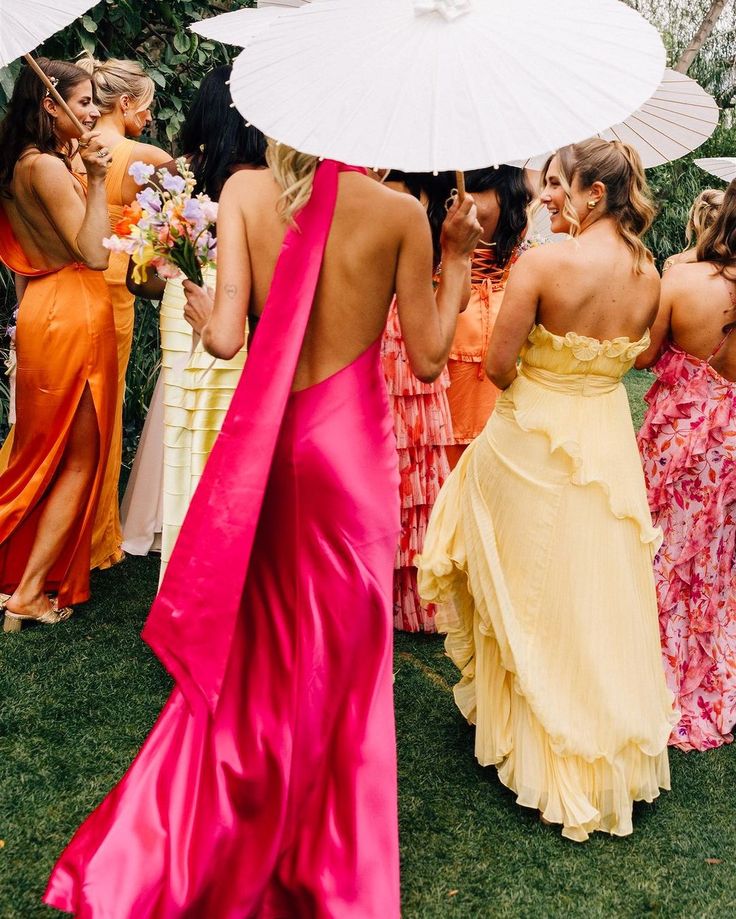 a group of women standing around each other holding umbrellas in their hands and wearing dresses