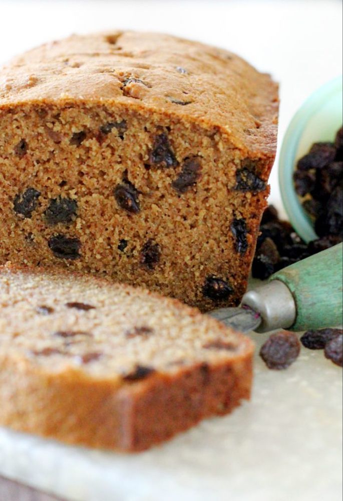 a loaf of bread sitting on top of a cutting board next to raisins