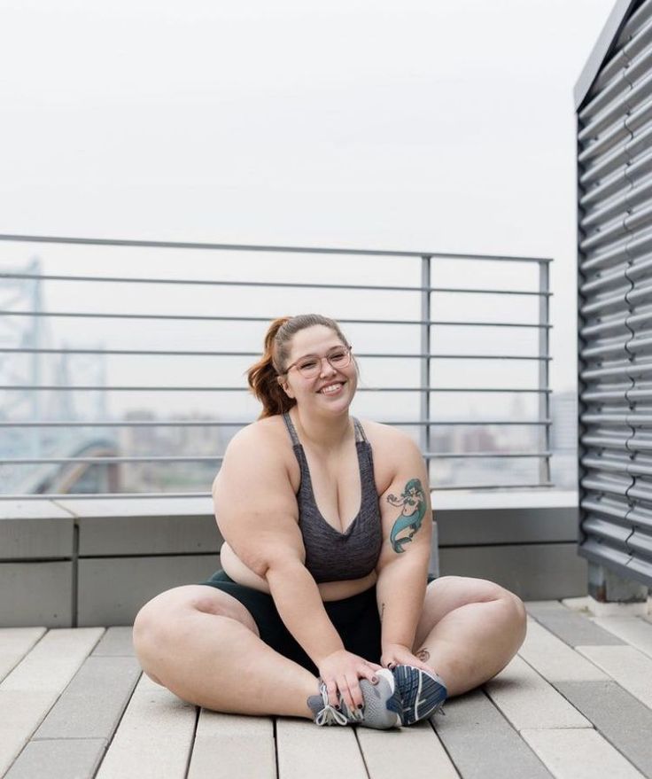 a woman is sitting on the ground with her legs crossed and smiling at the camera