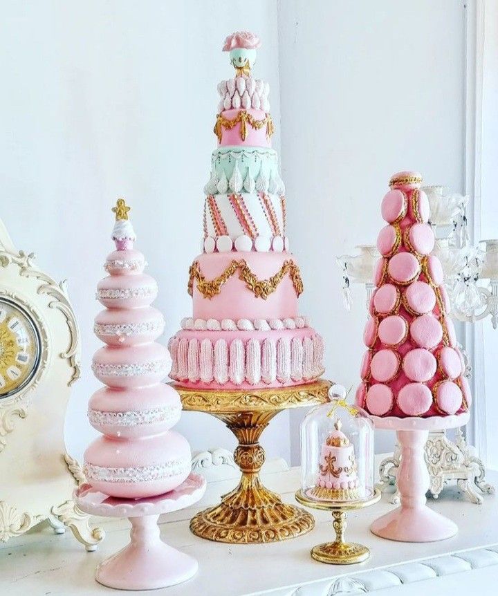 there are many different types of cakes on the table together, including one with pink frosting and gold trimmings