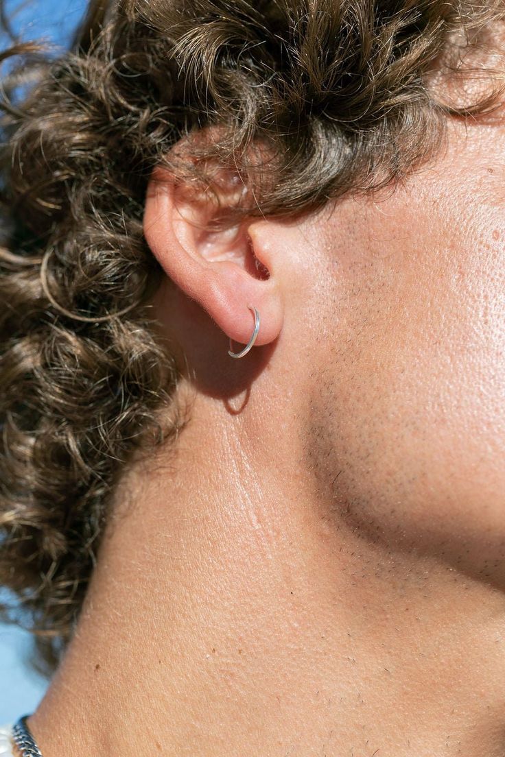 a close up of a person with curly hair wearing a necklace and earring set