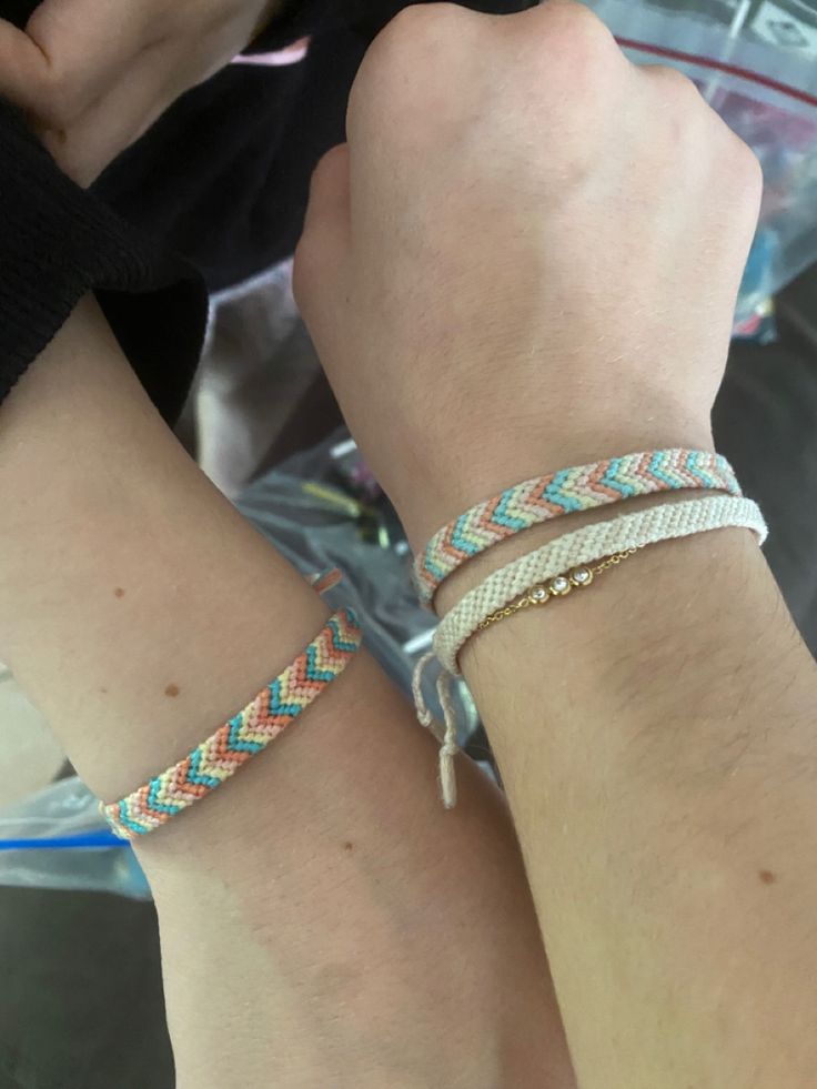 two people wearing bracelets on their wrist and one is holding the other's hand