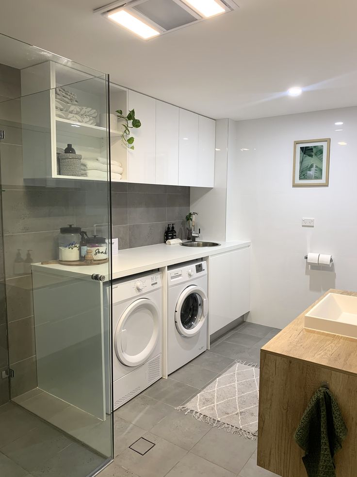 a washer and dryer sitting in a bathroom next to a sink with a mirror on the wall