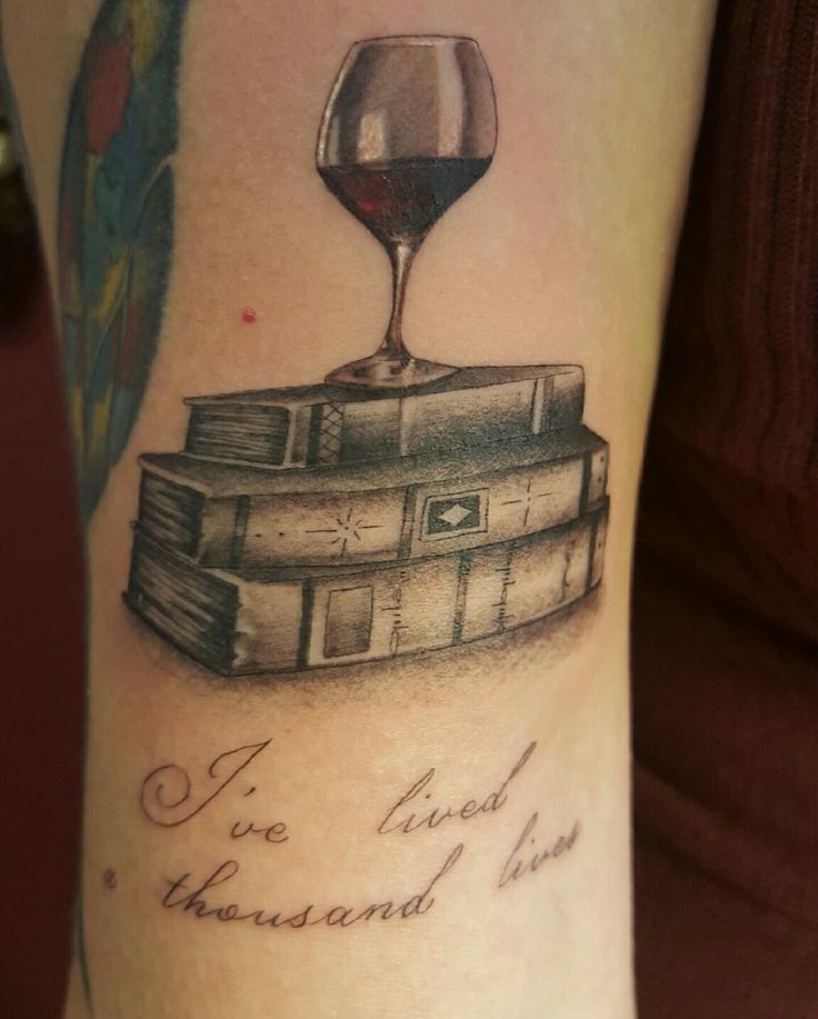 a tattoo with a wine glass on top of books and the words i've lived thousand lives