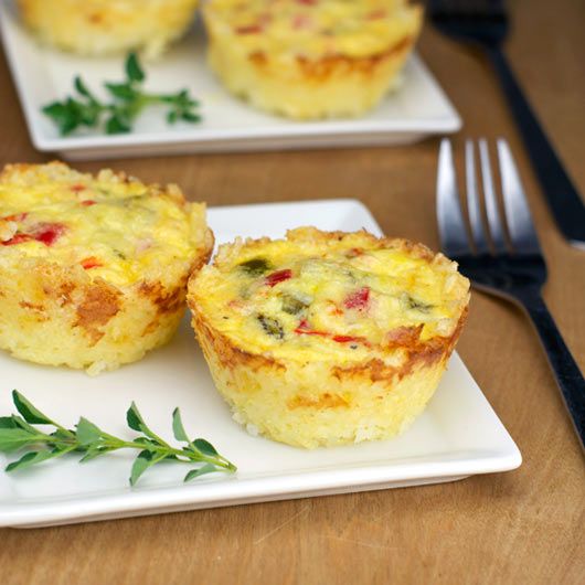 two white plates topped with mini quiches on top of a wooden table