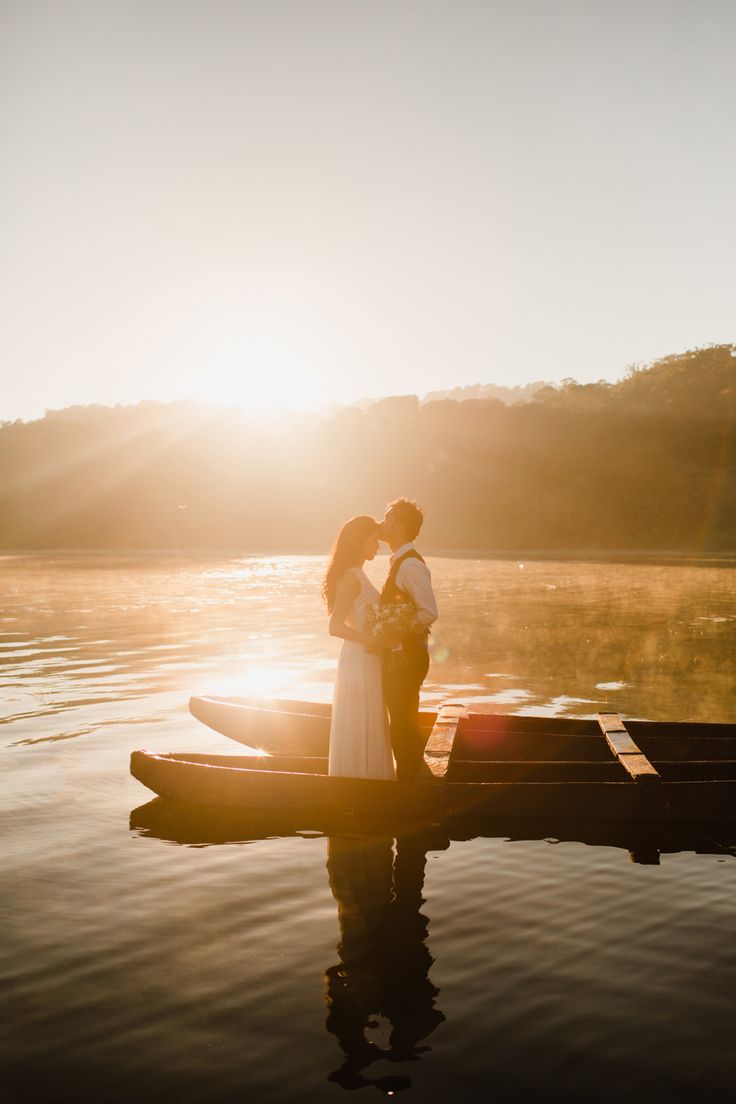 a man and woman standing on top of a boat in the middle of a lake