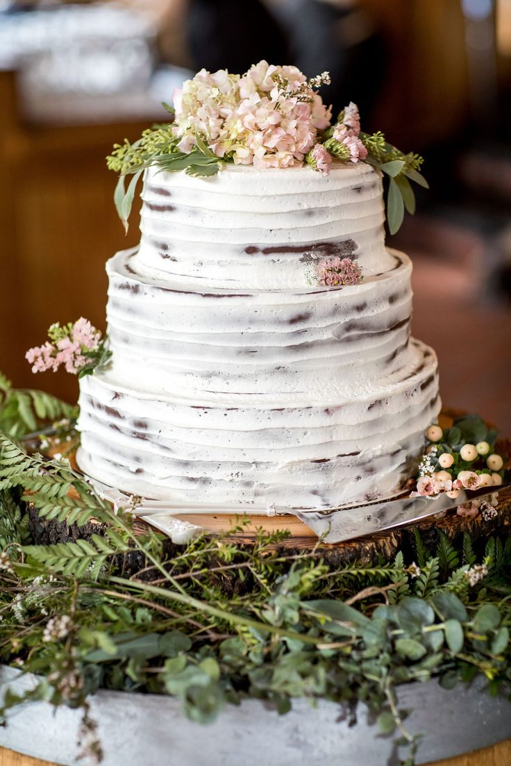 a white wedding cake with flowers and greenery