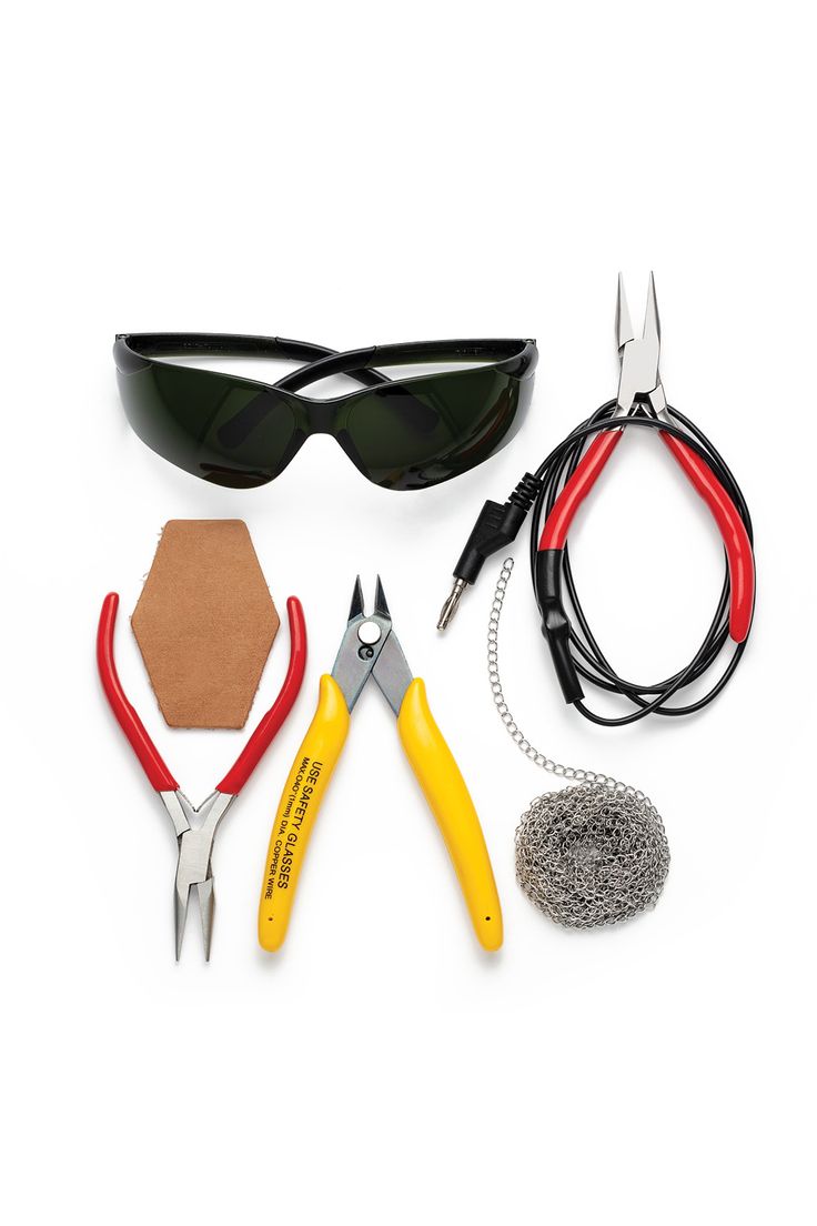 various tools are laid out on a white surface including sunglasses, wire, and other items