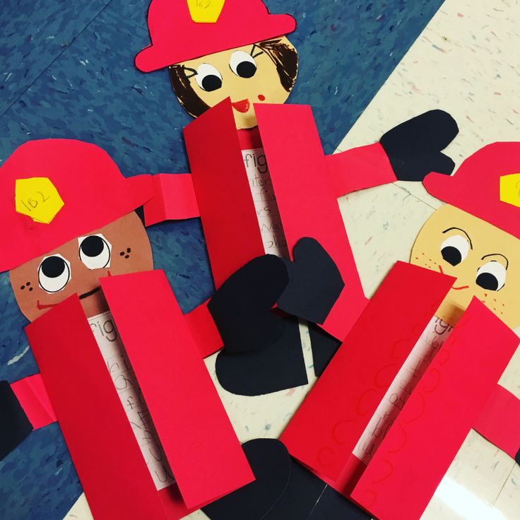 paper cut out people with fireman hats and red sticks on their heads, standing next to each other