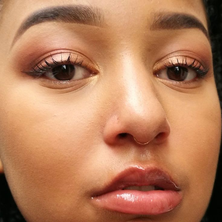 a close up shot of a woman's face with brown eyes and nose piercings