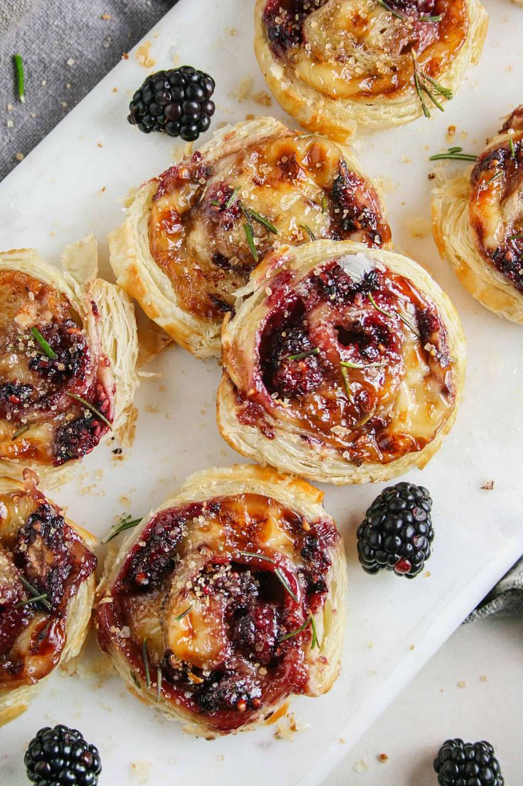 small pastries with blackberry toppings on a cutting board next to some blackberries