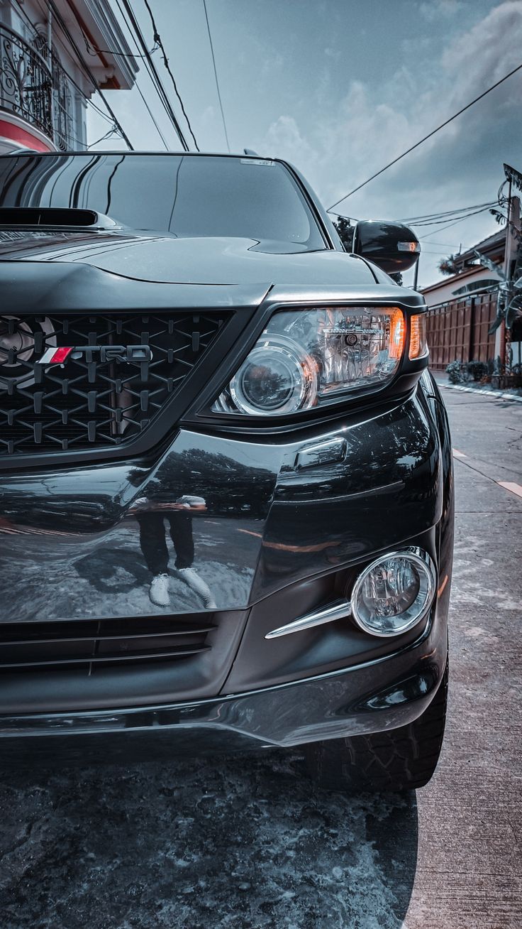 the front end of a black car parked on a street