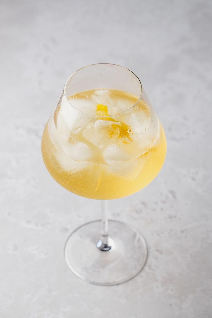 a close up of a drink in a glass with ice and lemons on the rim