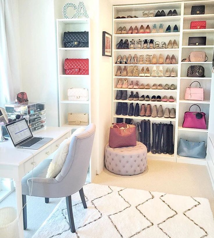 a white desk and chair in a room with shelves full of purses, handbags and shoes