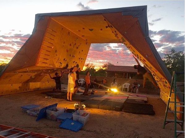 a group of people standing in front of a tent at night with the sun setting