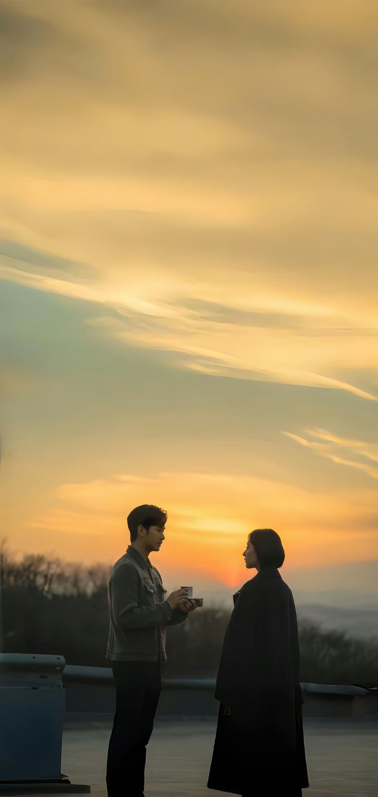 two people standing next to each other at sunset